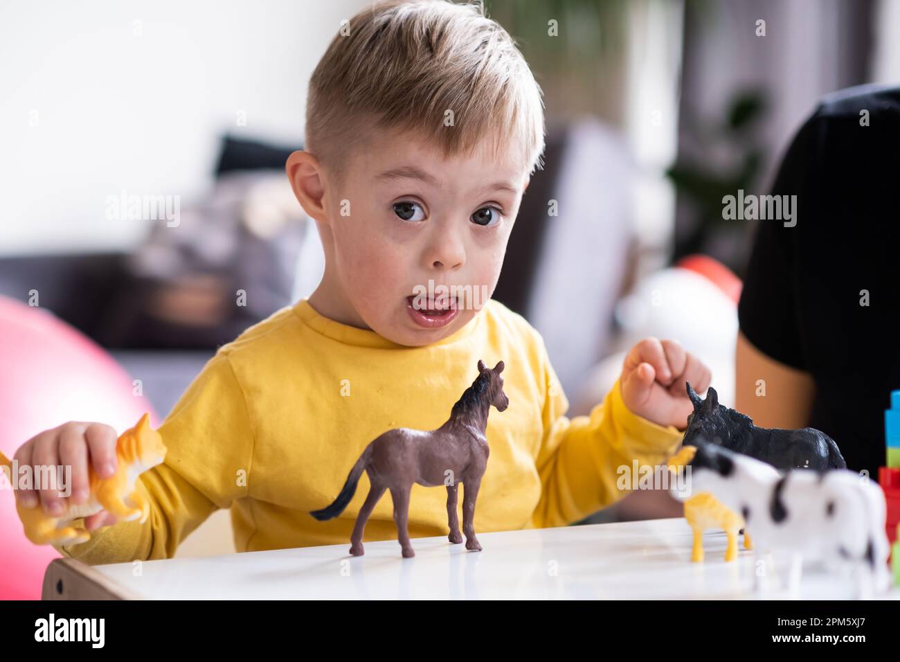 Little boy living with down syndrome playing toys at home. creativity