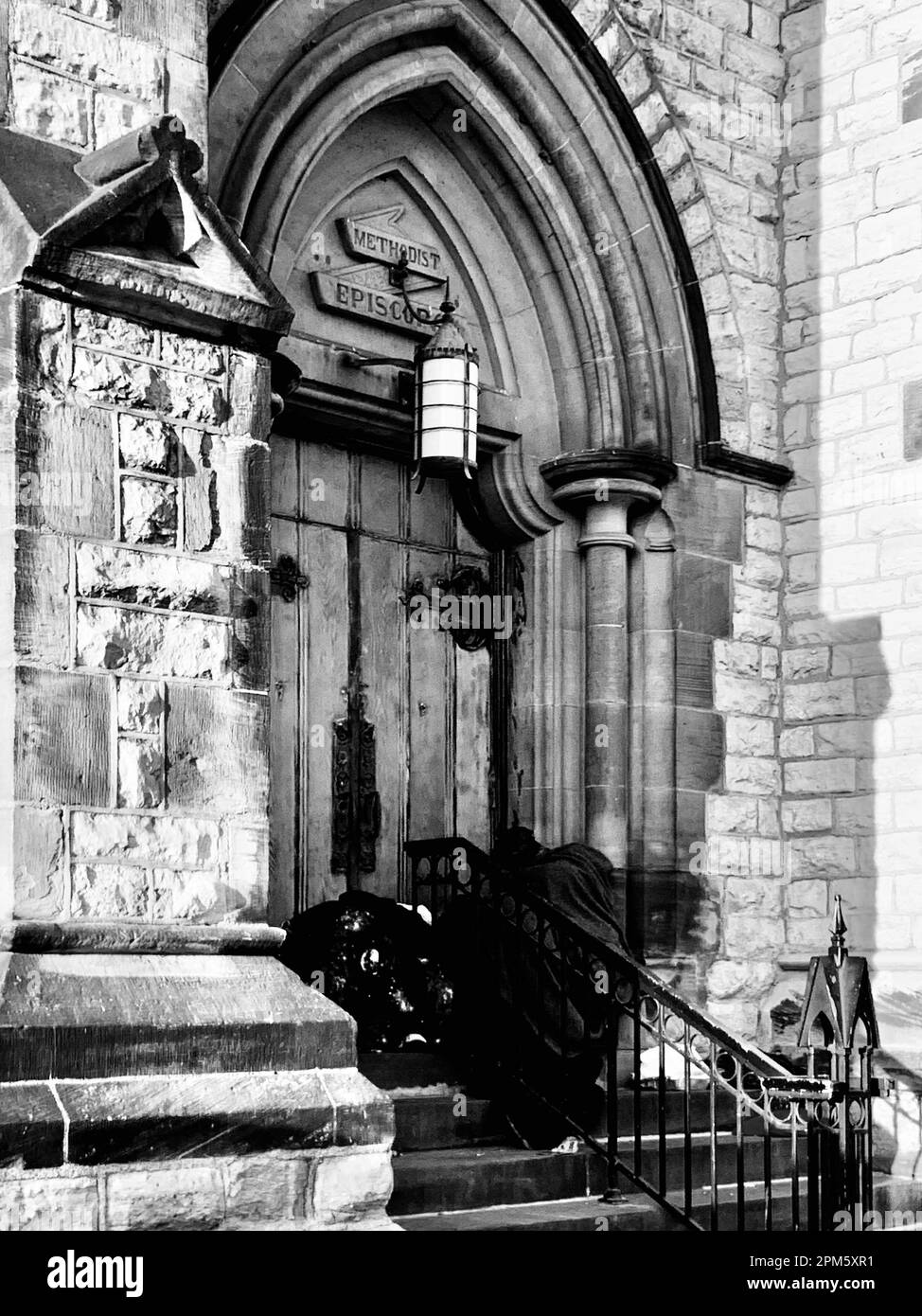 Cold homeless man sleeping at doorstep of cathedral Stock Photo