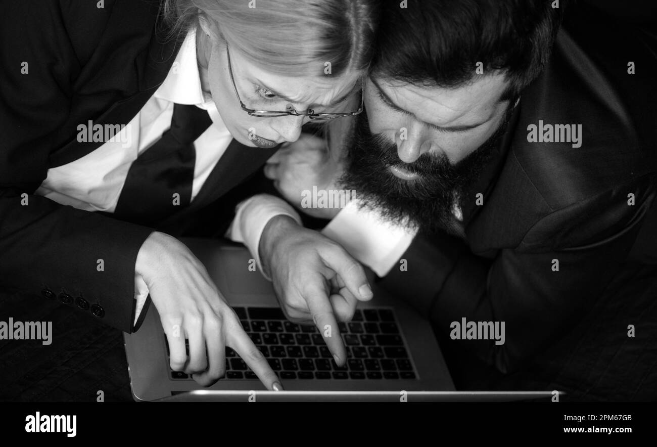 The more bet is the more winning will be. Man and woman managers with laptop working on black background isolated. Two managers working on laptop Stock Photo