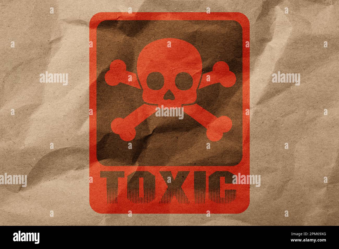 Hazard warning sign (skullandcrossbones symbol and word TOXIC) on crumpled kraft paper, top