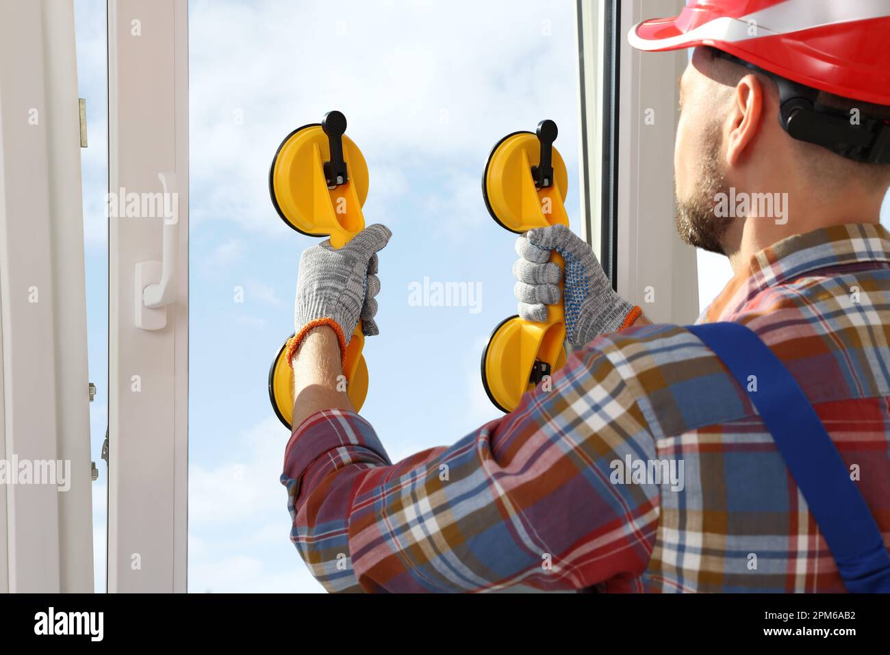 Worker using suction lifters during plastic window installation indoors Stock Photo