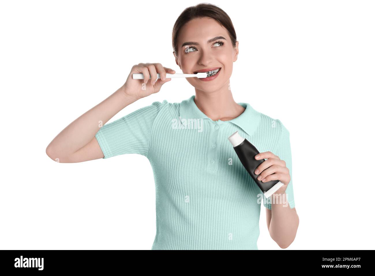 Young woman brushing teeth with charcoal toothpaste on white background