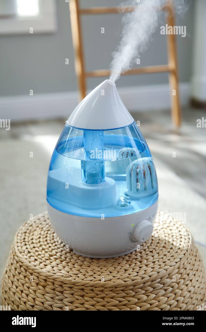 Modern air humidifier on wicker pouf indoors Stock Photo - Alamy