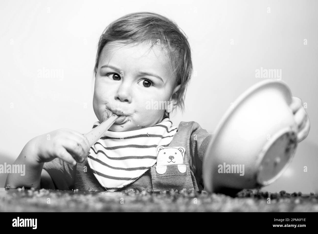 Beautiful baby eating. Happy baby eating himself with a spoon Stock