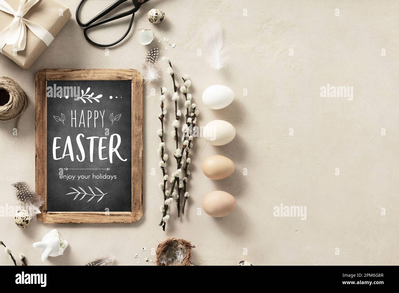 Easter composition with vintage Easter decorations and Happy Easter chalk board on beige stone background top view flat lay copy space Stock Photo
