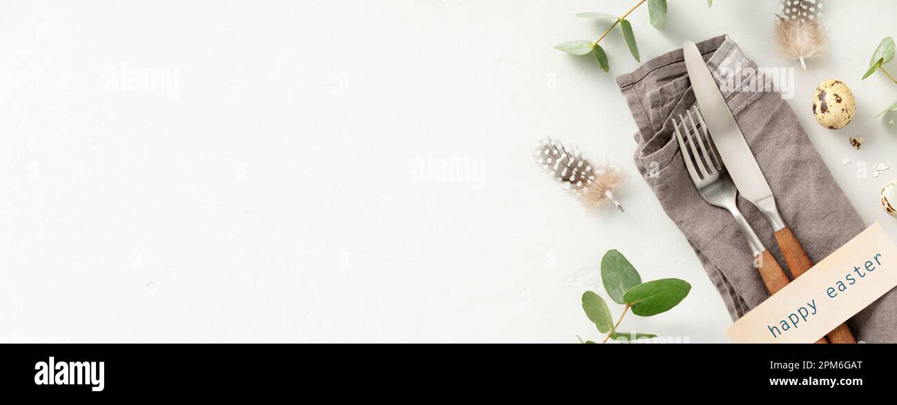 Easter table decorations. Stylish Easter brunch table setting with vintage cutlery, easter eggs and spring branches on light grey background top view Stock Photo