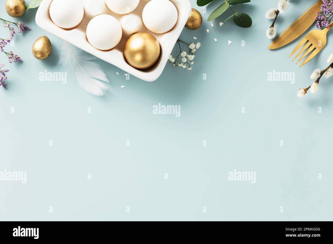 Easter table decorations. Happy Easter concept with golden table setting, easter eggs, feathers and spring flowers. Easter background with copy space. Stock Photo