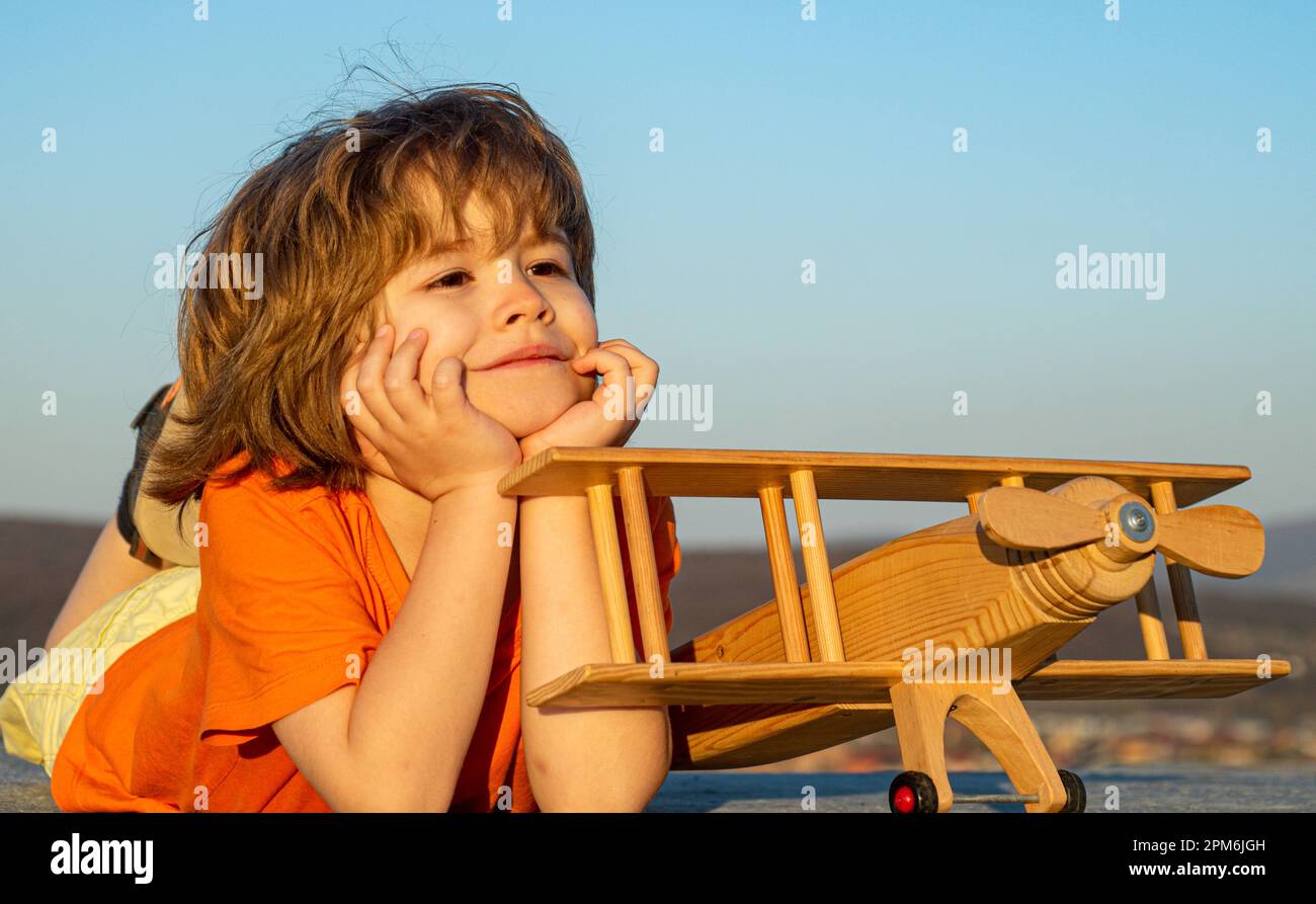 Child boy playing with wooden toy airplane, dream of a pilot