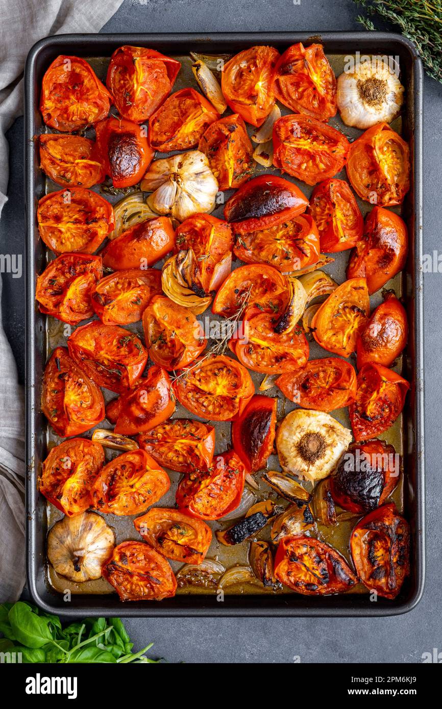 Tomatoes, onion and garlic roasted on a baking sheet Stock Photo - Alamy