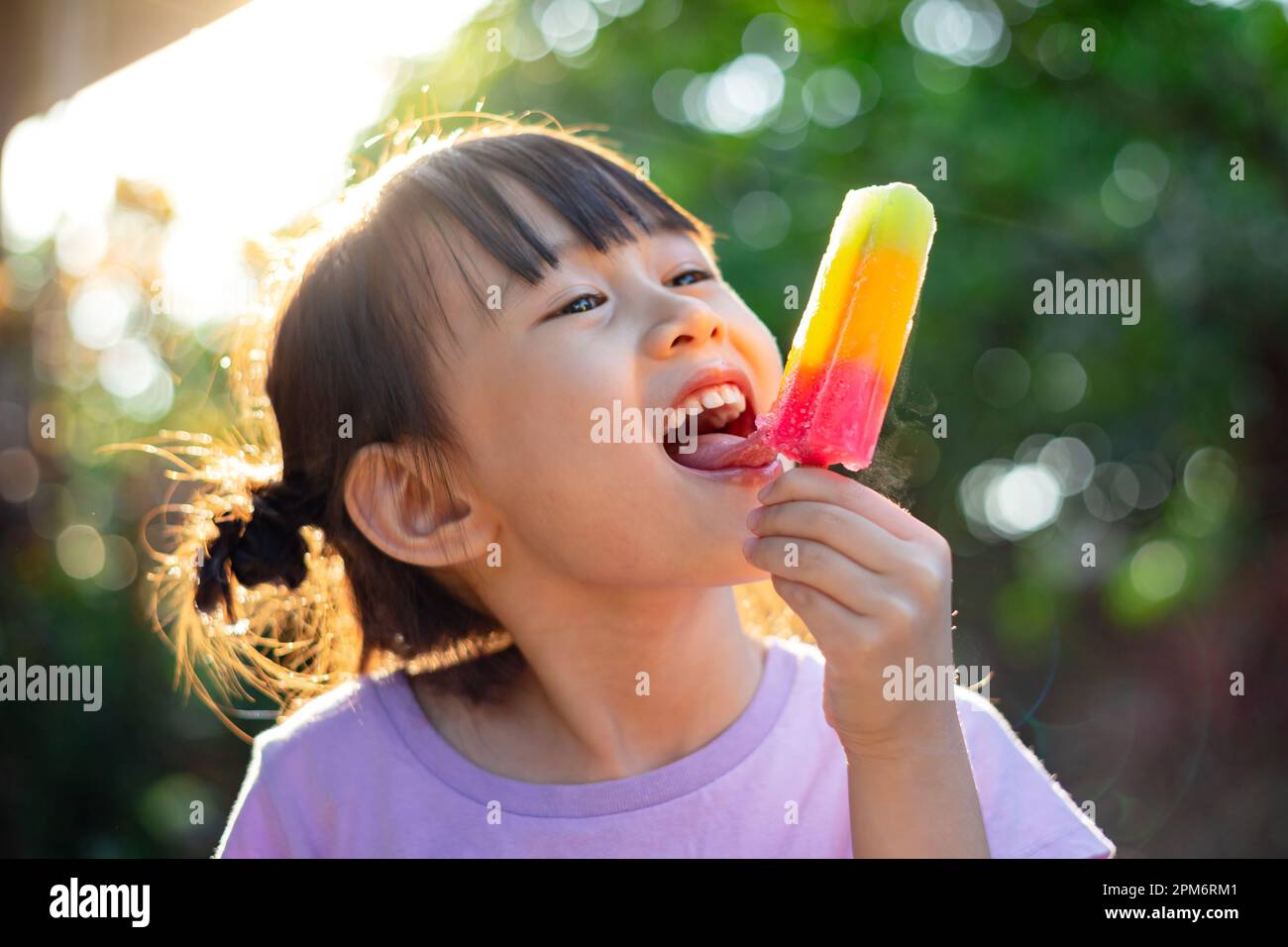 Cute happy baby girl eating ice cream popsicle in summer. Picture for concept of sweet, fat, obesity and diabetes in children. Stock Photo
