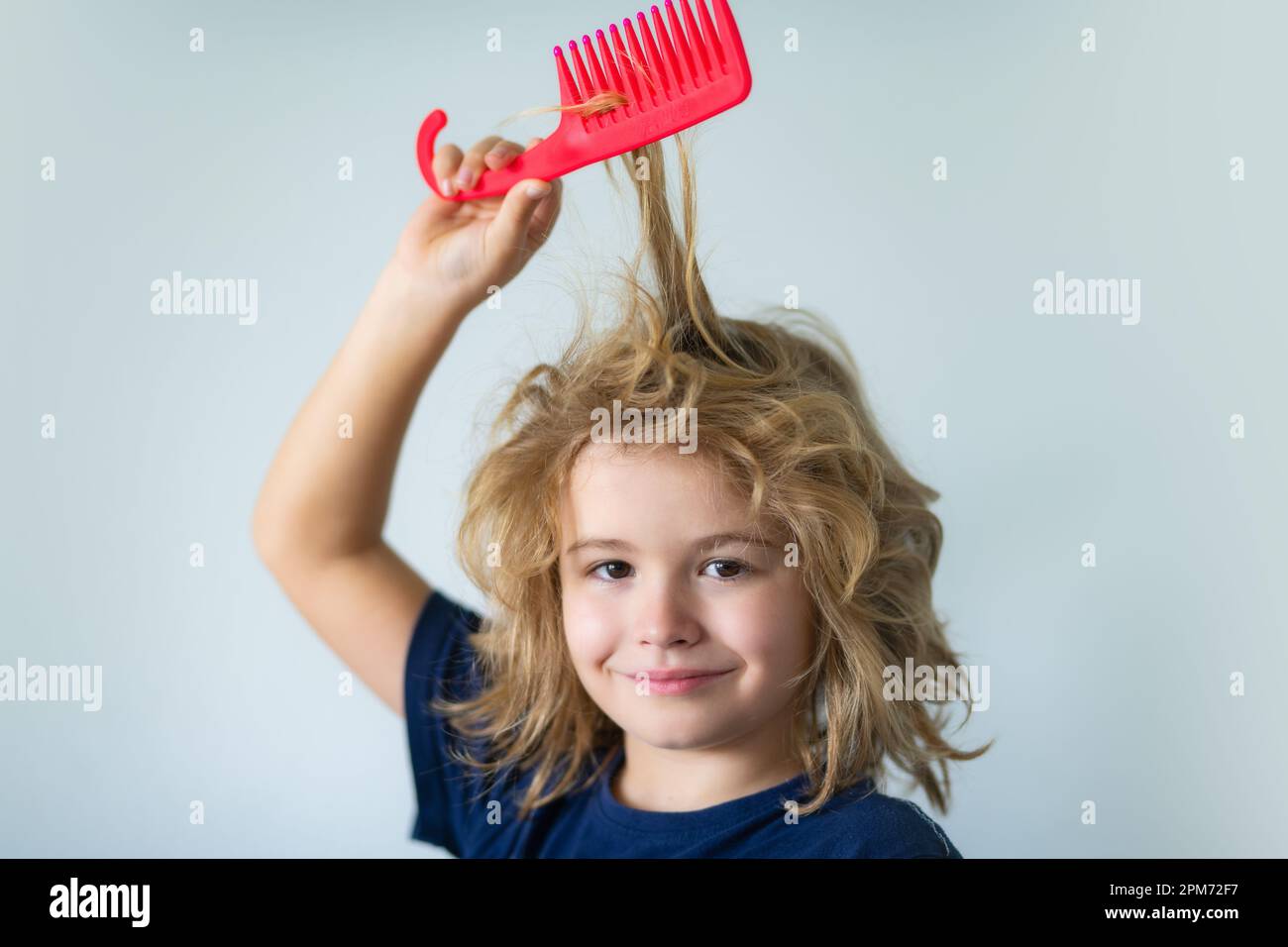 Tangled kids hair. Cute child with comb. Blonde kid combs unruly hair