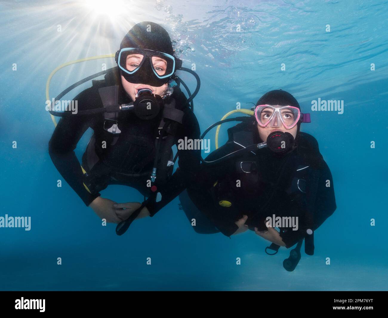 Closeup of two scuba divers underwater swimming towards the camera with