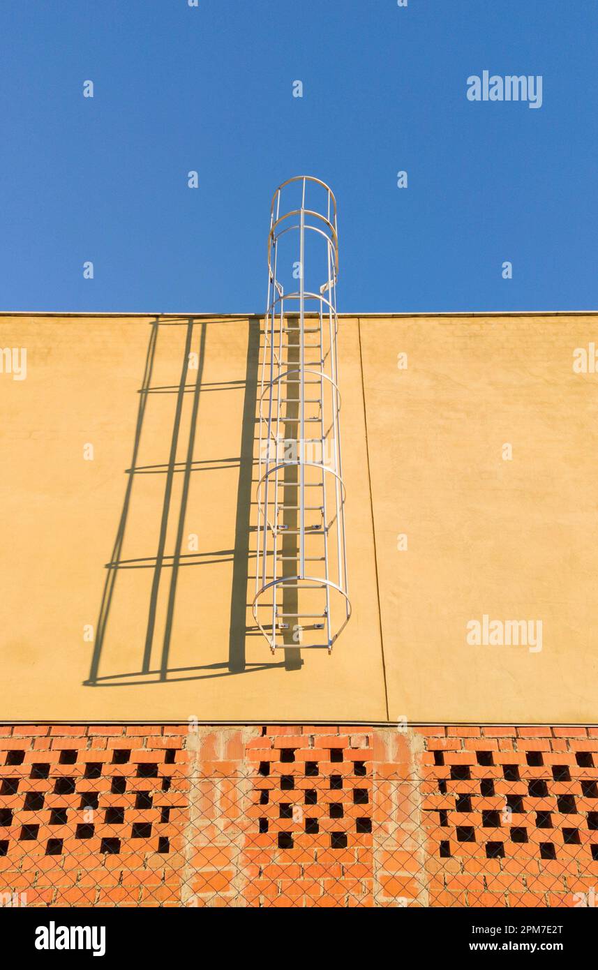 Service ladder installed on a commercial premises under construction. Blue sky background. Stock Photo