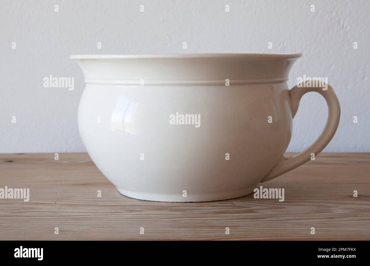 White porcelain camber pot over wooden surface. Selective focus. Stock Photo