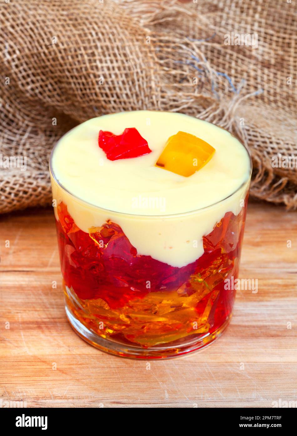 jelly and custard in glass cup on rustic surface with burlap Stock Photo