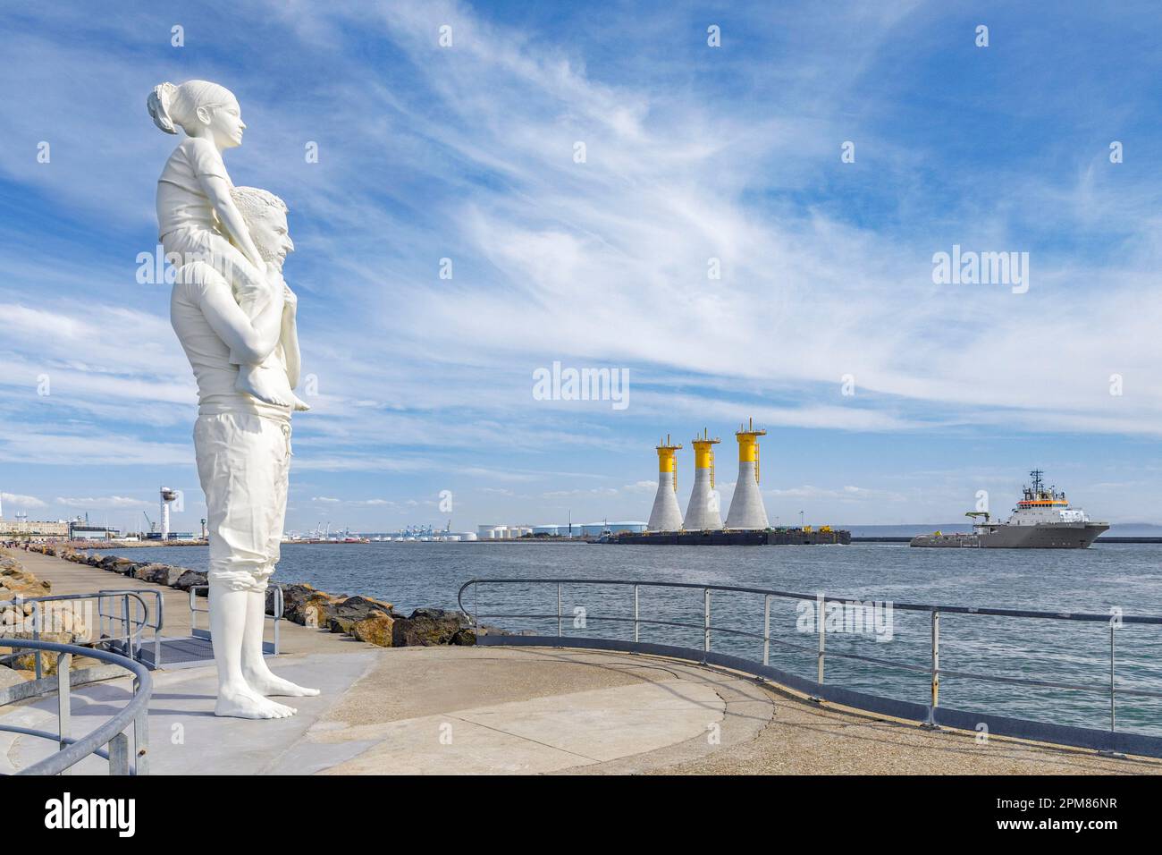 France, Seine-Maritime (76), Le Havre, the port, Augustin Normand dyke, Until the End of the World statue, a father and his daughter, sculpted by Fabien Merelle, observe a tugboat towing 3 gravity-based structures (GBS) towards the offshore wind farm of Fécamp Stock Photo