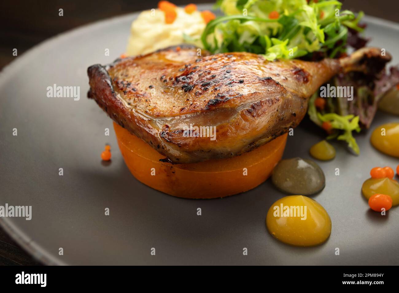 Flavorful duck leg dish with crispy skin and vibrant produce Stock