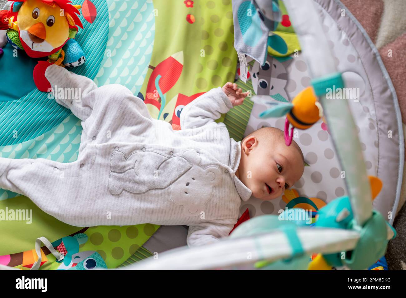 newborn baby lying on her back in a playground, baby gym to stimulate