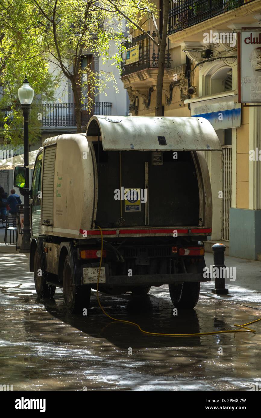Back of a cleaning truck from the municipal service brigade of Barcelona, cleaning a pedestrian street with the hose watering the entire street. Stock Photo