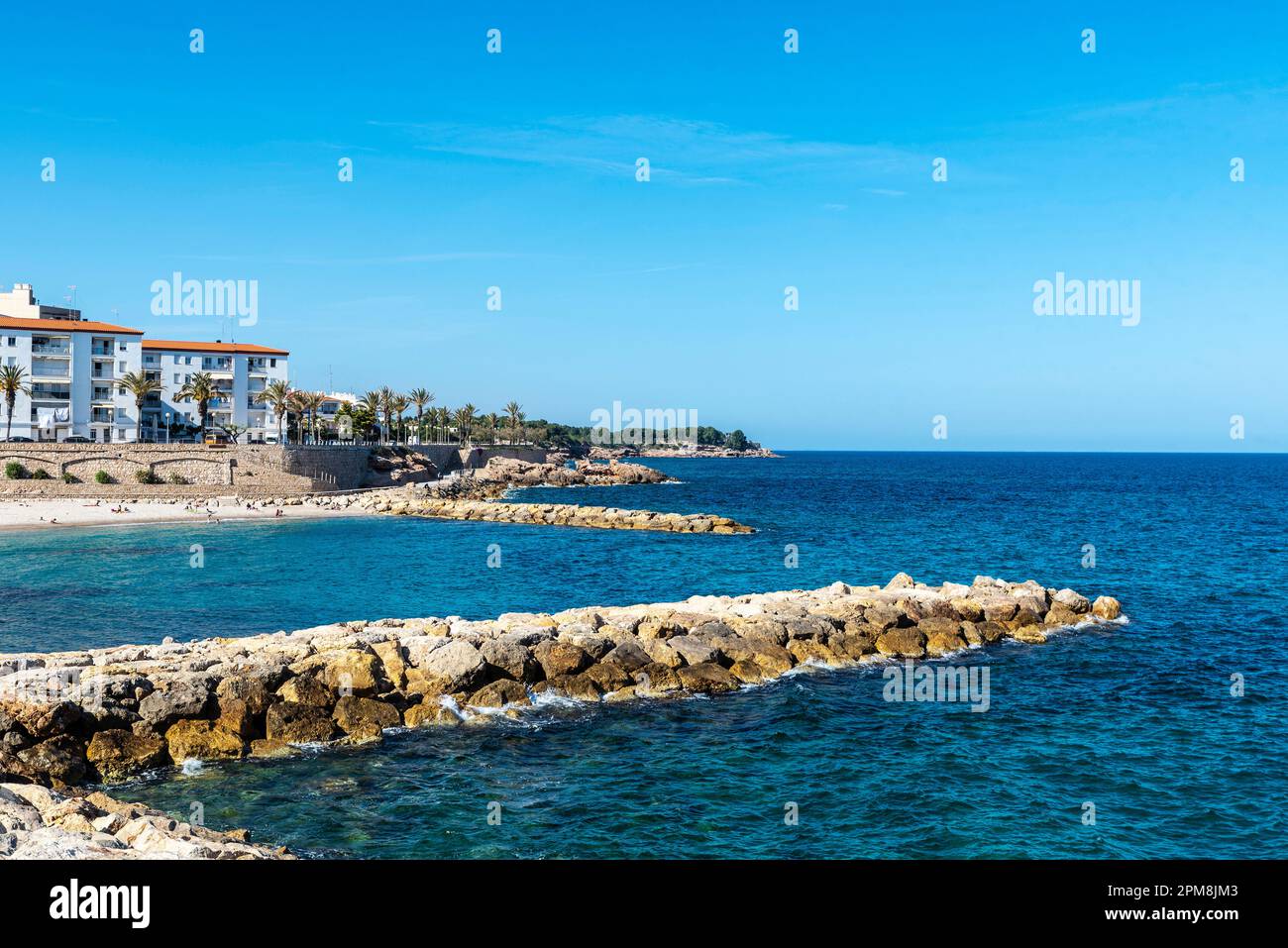 Beach and breakwaters with people around in Ametlla de Mar, Tarragona
