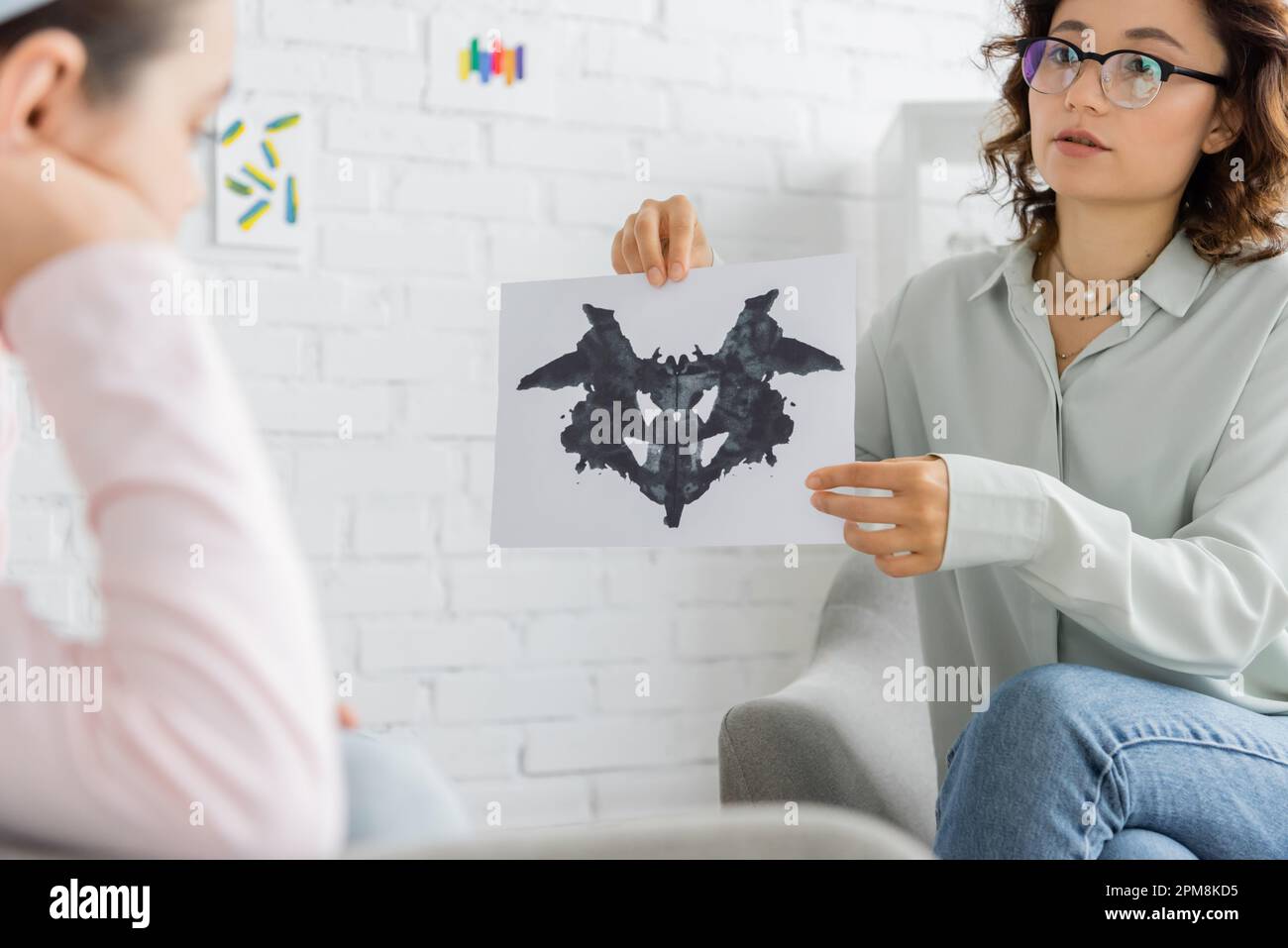 Psychologist holding Rorschach test near blurred preteen girl in