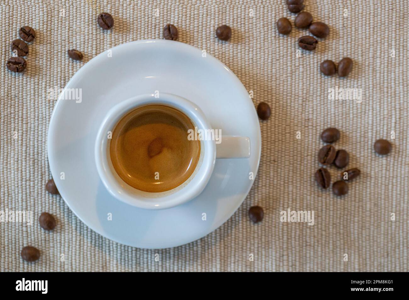 eine mit leckerem Espresso gefüllte Tasse von oben, auf einem Tischset Stock Photo