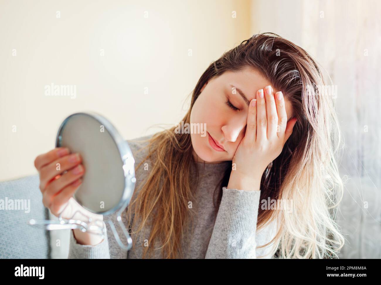 Stressed woman is sad about dirty oily and greasy hair looking in