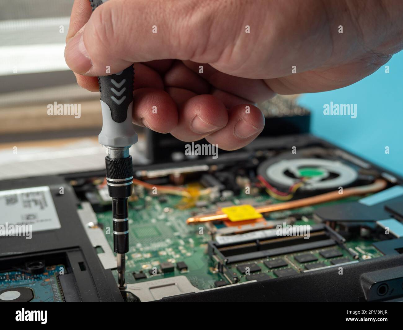 The master repairs a broken laptop with a screwdriver. Specialist and