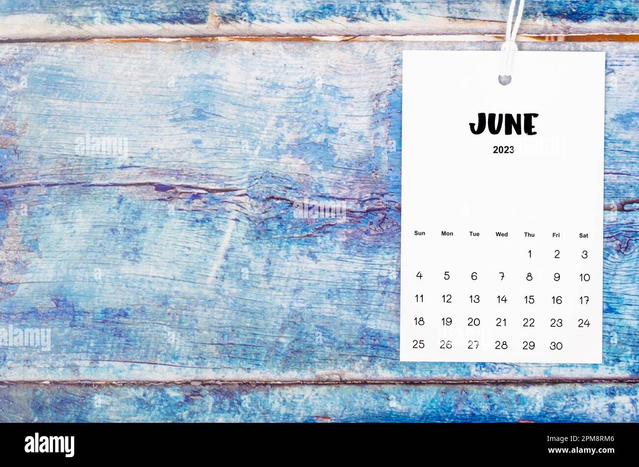 June 2023 calendar page hanged with white rope on old blue wooden