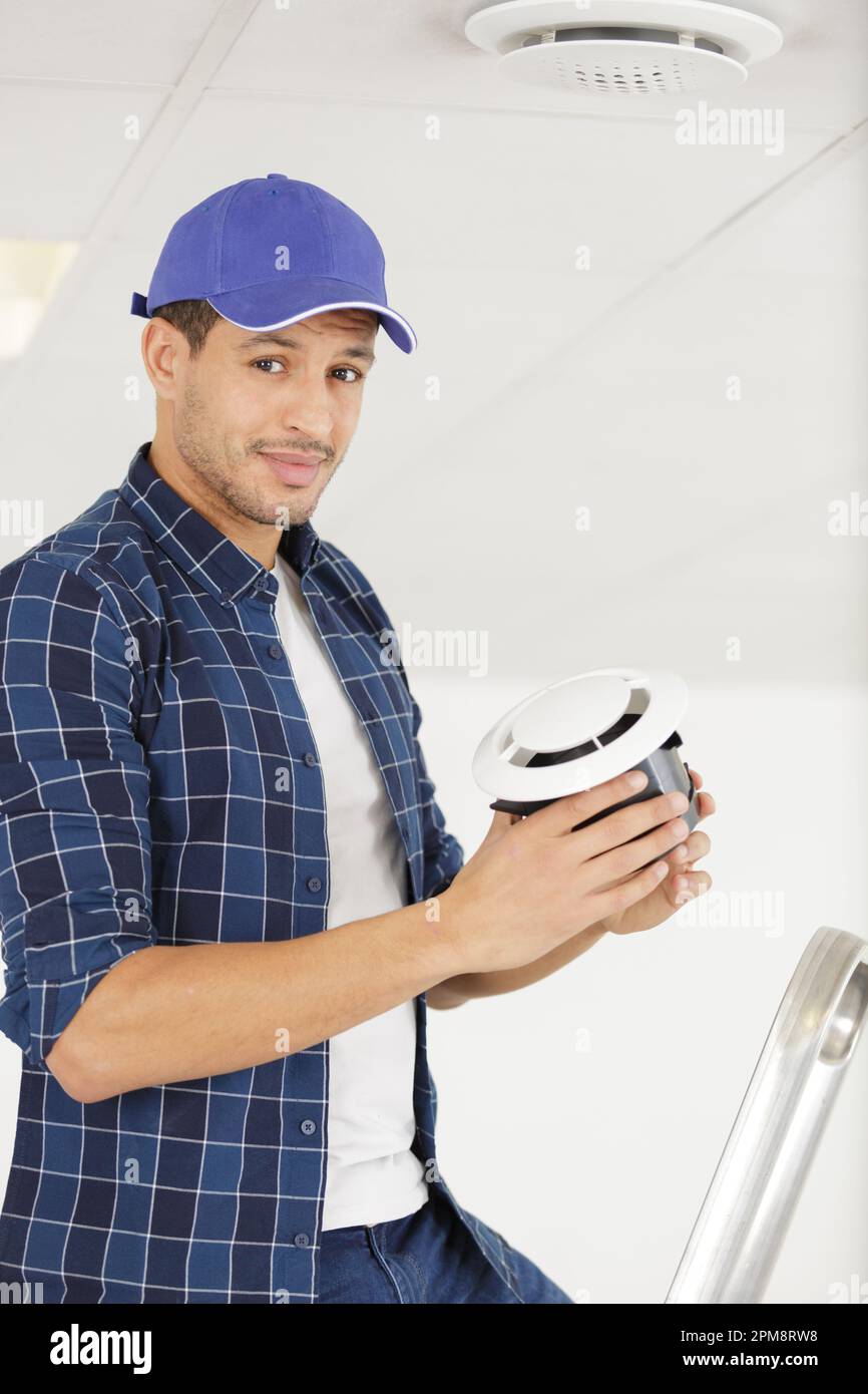 young repairman changing filter for air conditioner Stock Photo