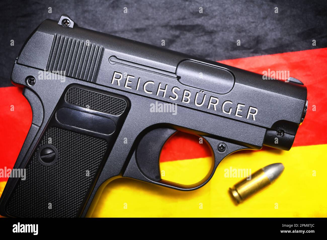 FOTOMONTAGE, Waffe mit Schriftzug Reichsbürger auf einer Deutschlandfahne Stock Photo