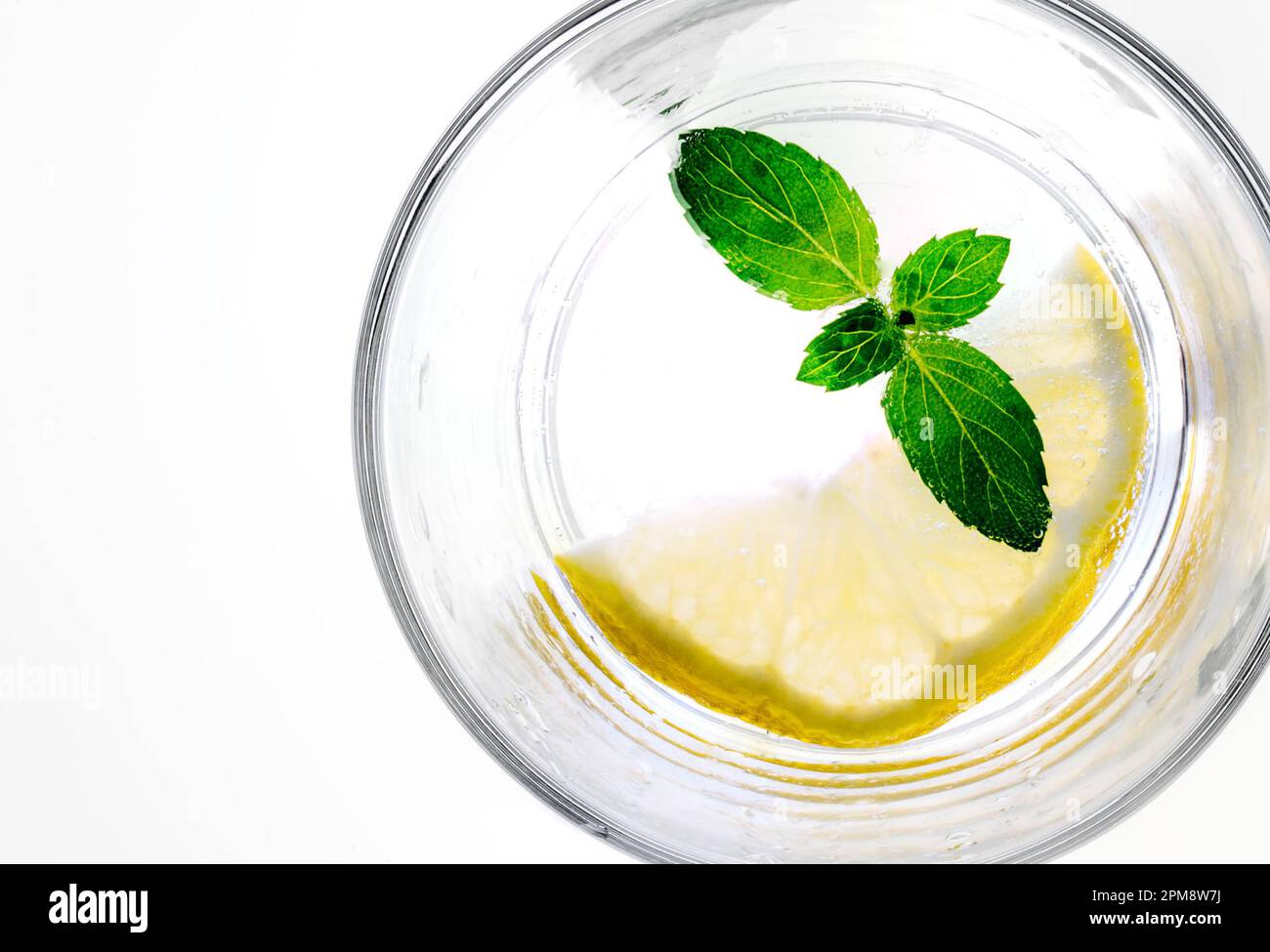 essenundtrinken-frisches klares wasser im glas mit einem spritzer zitrone  minze als sommerliche erfrischung zm trinken und geniessen Stock Photo
