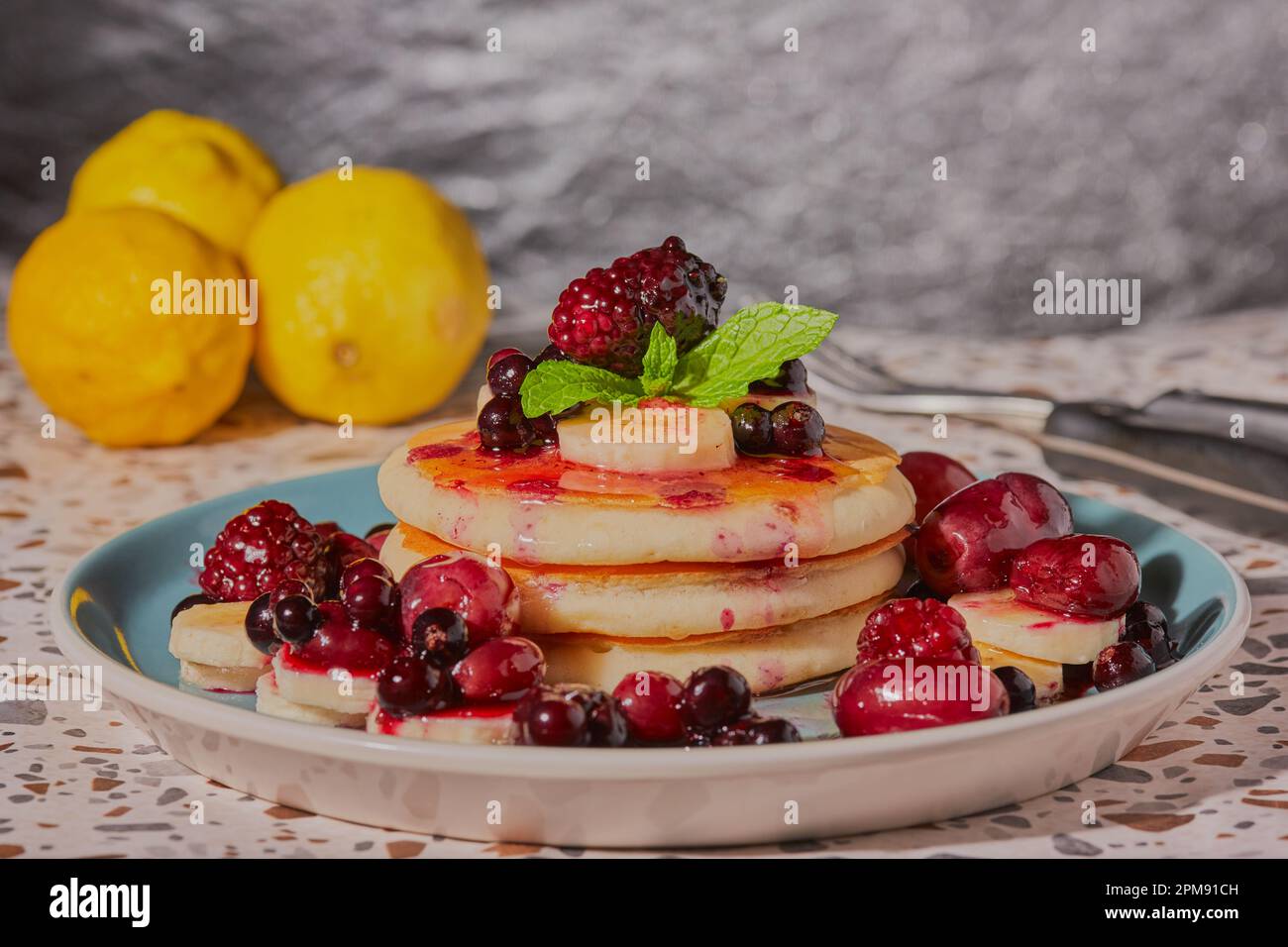Pancakes stacked up with honey banana and mixed berries and garnished with mint Stock Photo