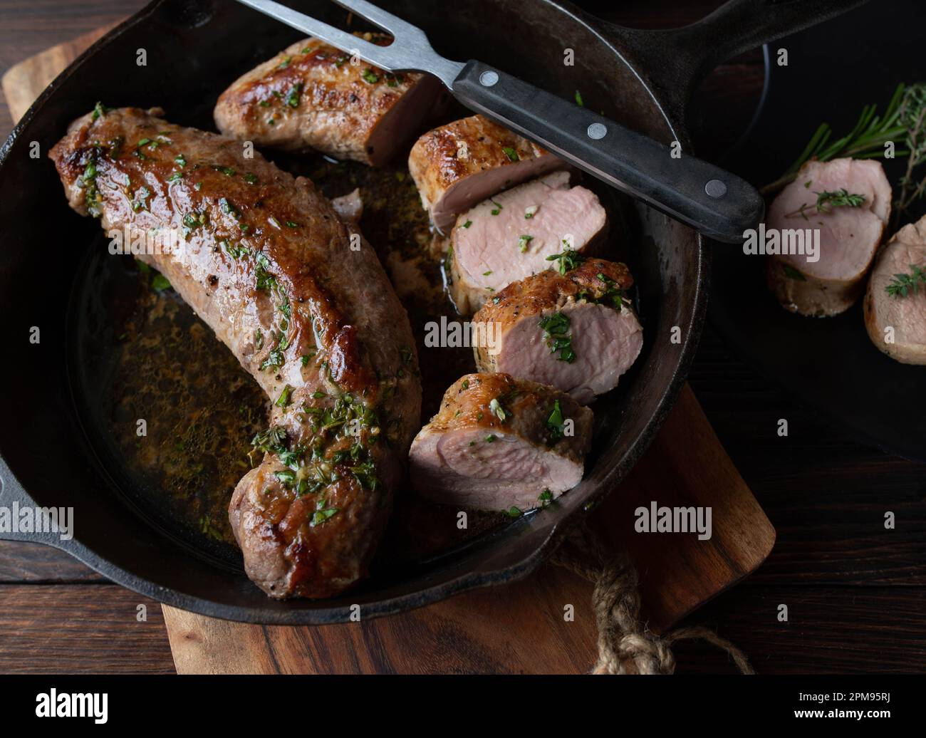 Pork fillet with herb butter in a cast iron pan Stock Photo