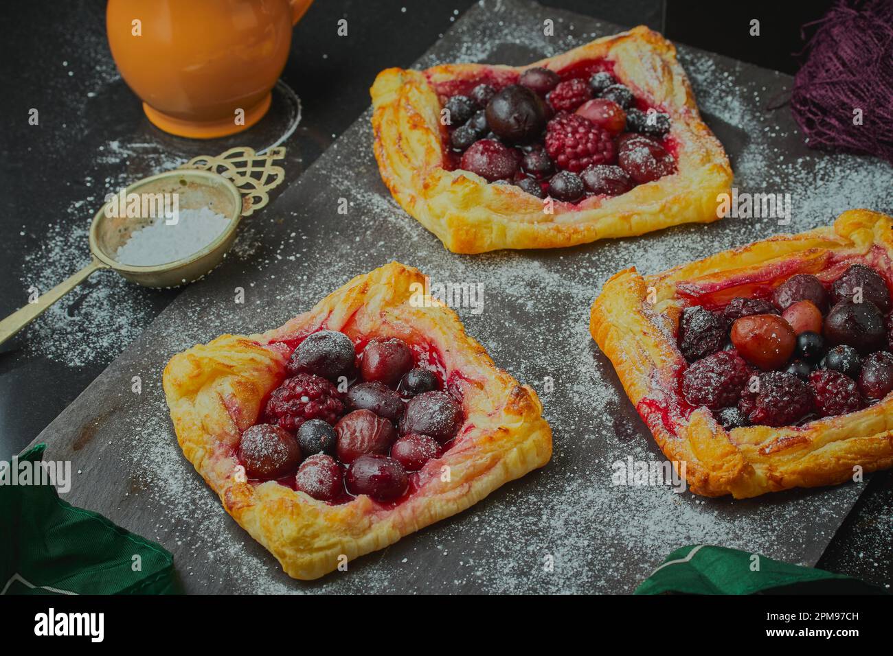 Mixed fruit tarts sprinkled with icing sugar. Stock Photo