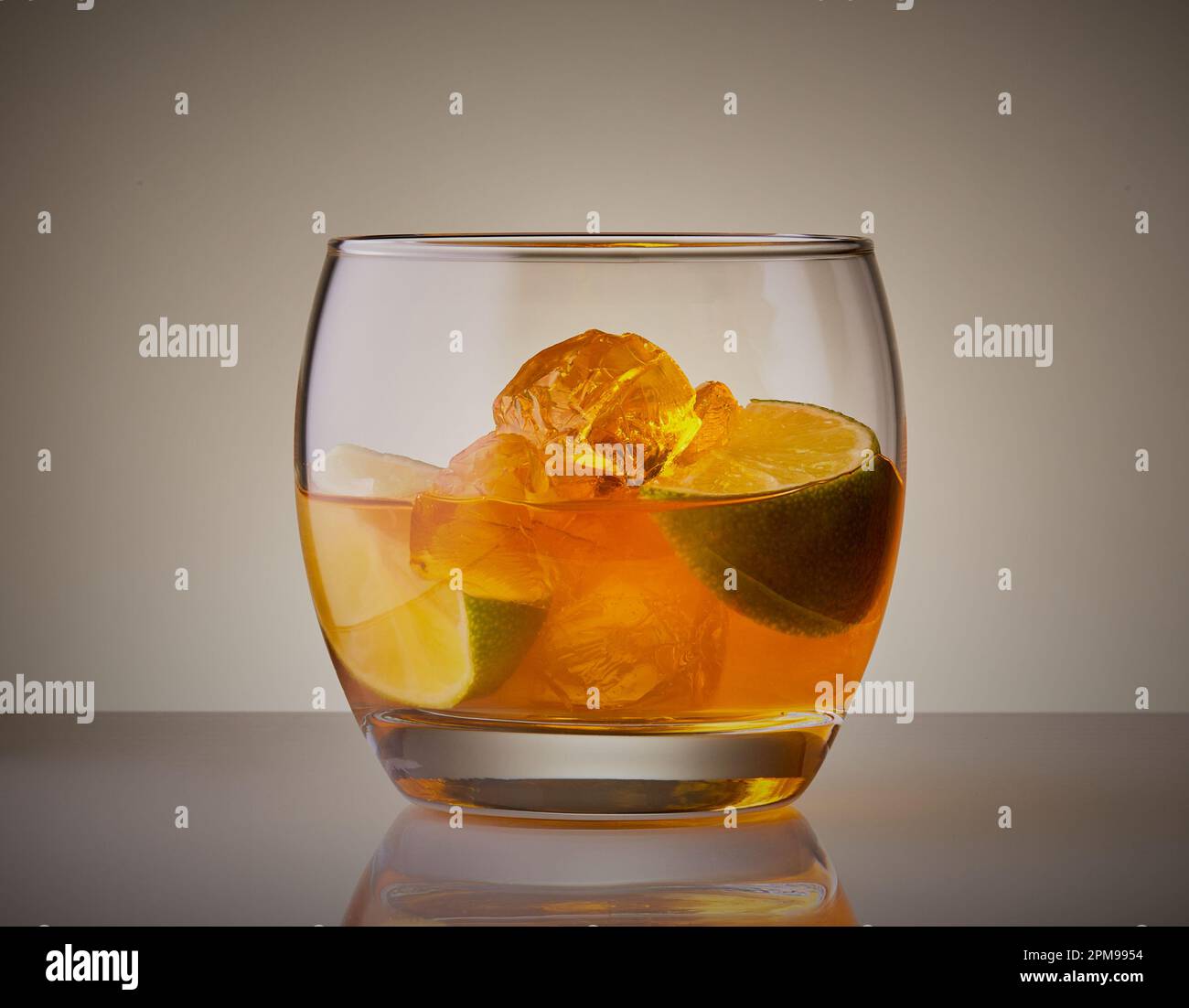 Whiskey cocktail in a nice cool tumbler glass with ice and citrus fruit segment. Stock Photo