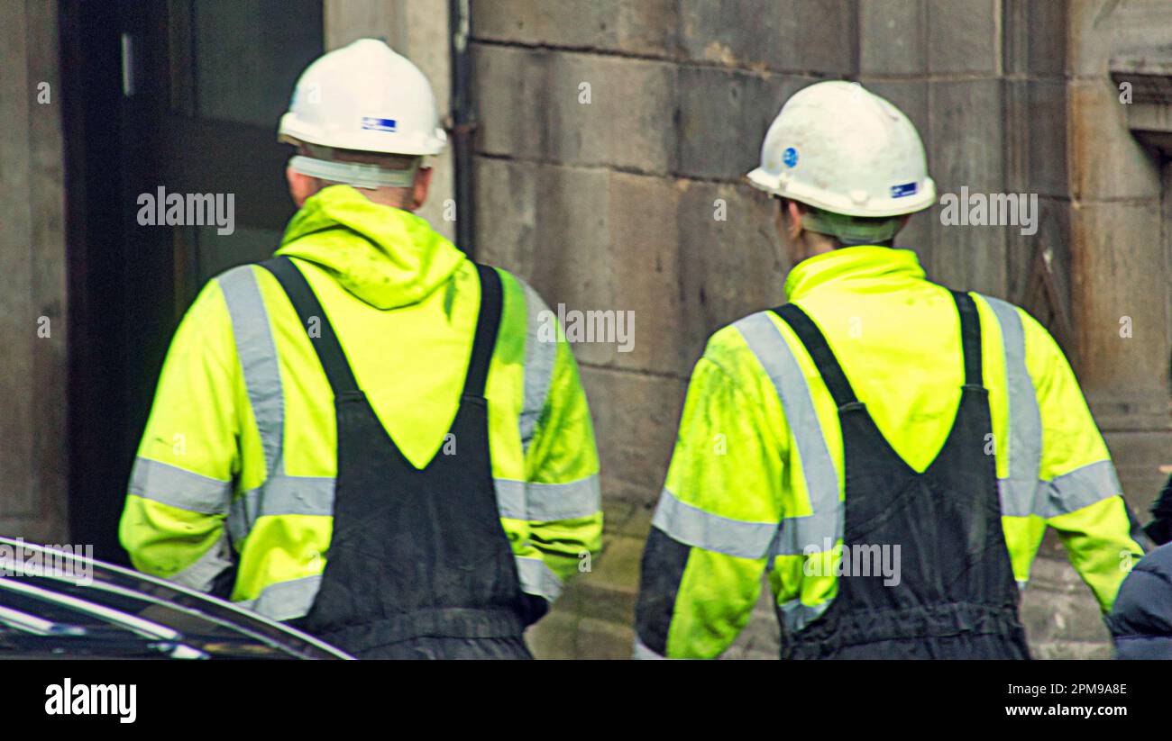 two workmen building workers un yellow vests and hard hats Stock Photo