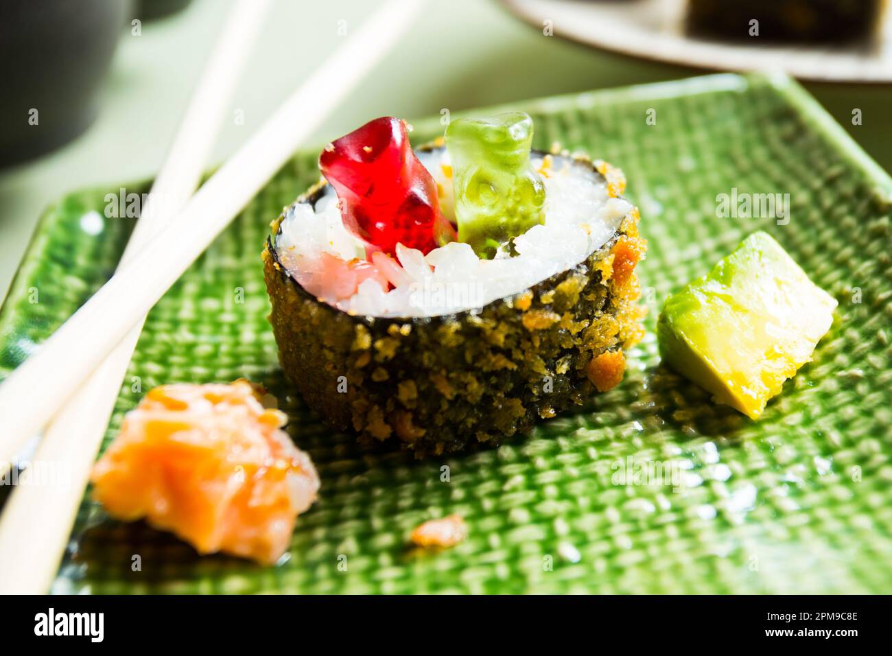 Gummy bears playing on a food table with a sushi hot roll. Stock Photo