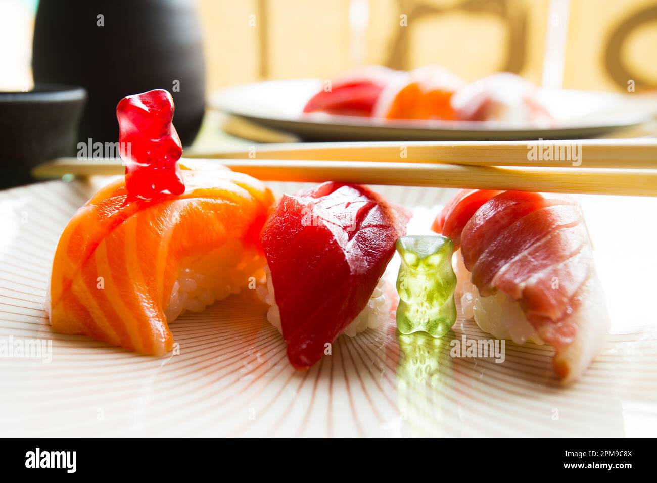 Gummy bears playing on a food table with three sushi nigiris. Stock Photo