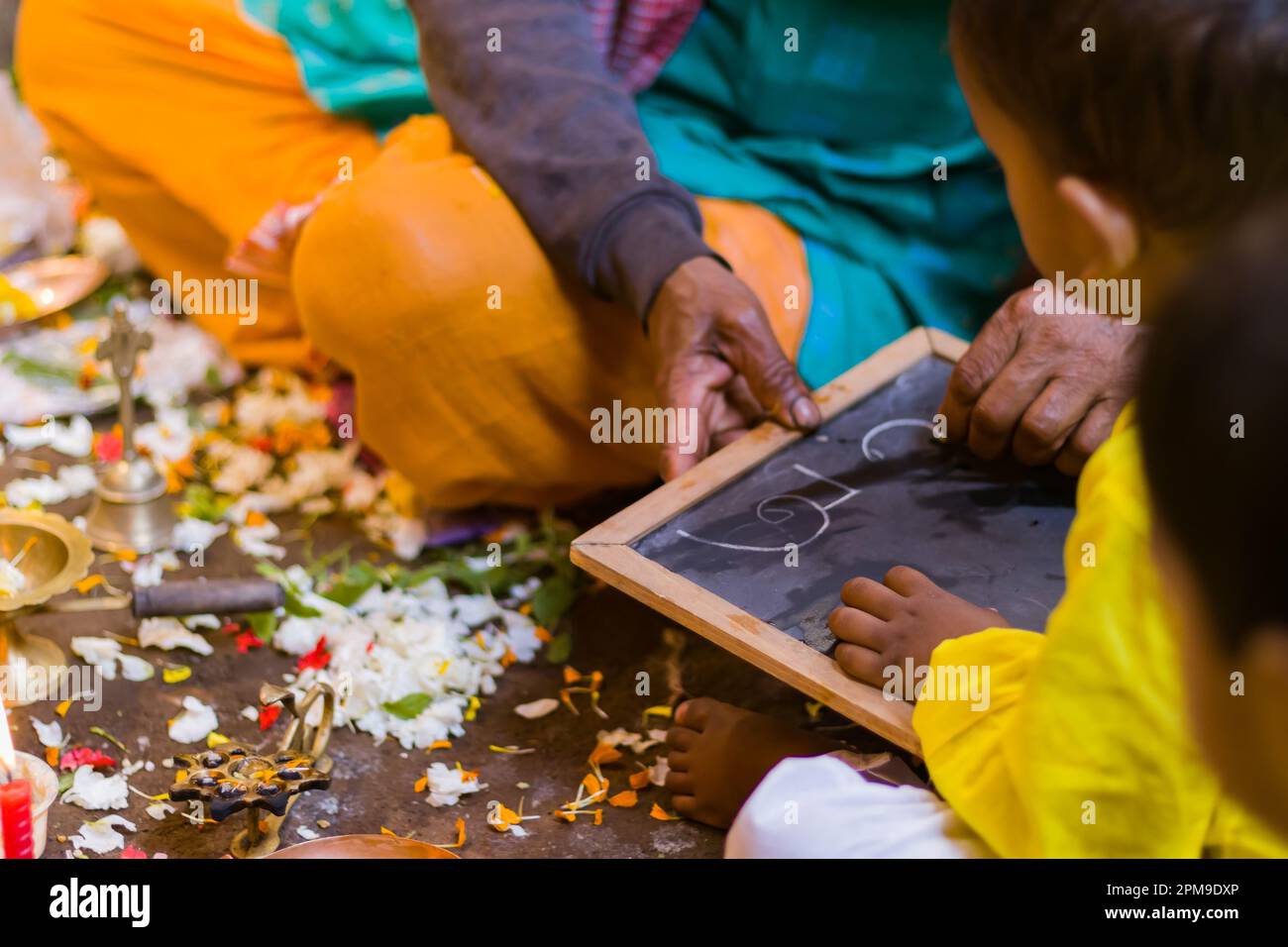 Aksharabhyasam or hate khori ritual is being performed to introduce education to young children during Saraswati Puja or vasant panchami. The priest i Stock Photo