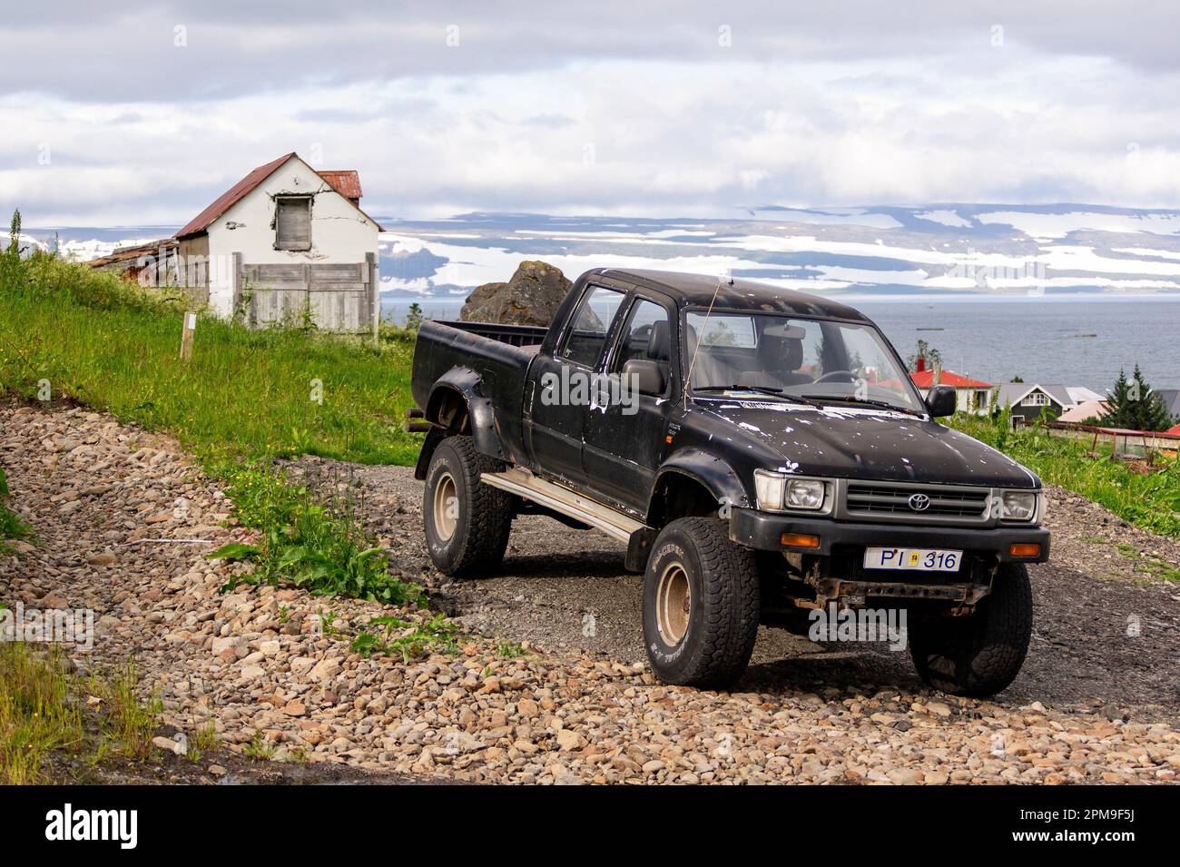 ISAFJORDUR, ICELAND - JULY 7, 2014: Black Toyota Hilux 2.4D pickup with huge tyres ready for adventure in Icelandic landscape Stock Photo
