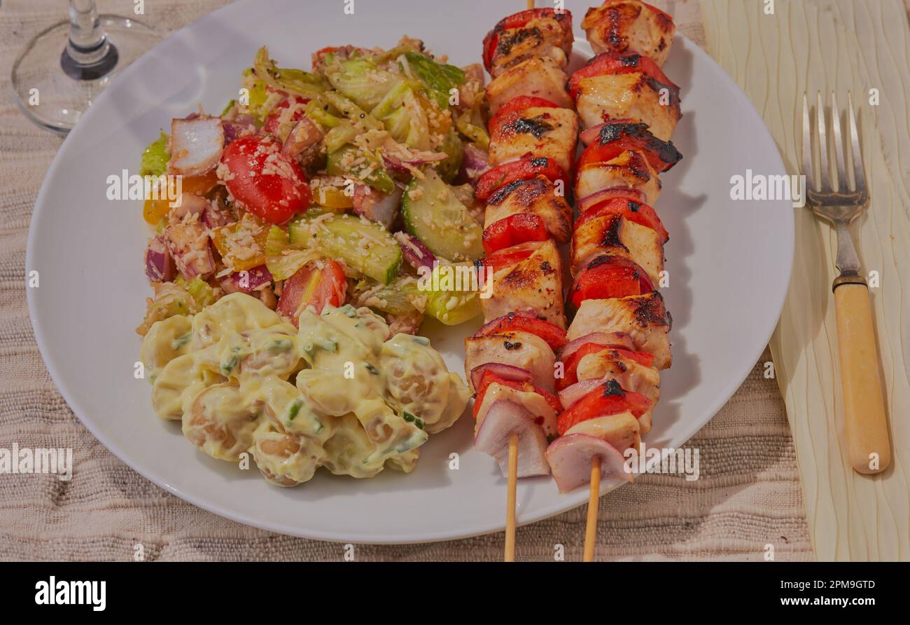 Yummy chicken kebabs with mixed salad and potato salad. Stock Photo