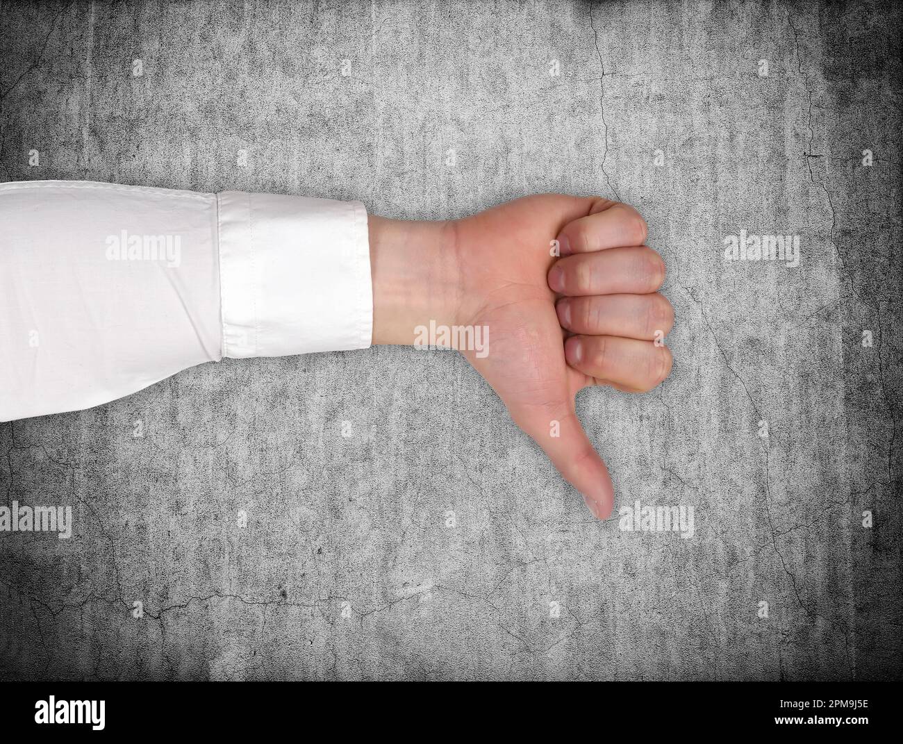 hand showing dislike sign, thumb down on gray wall background Stock Photo