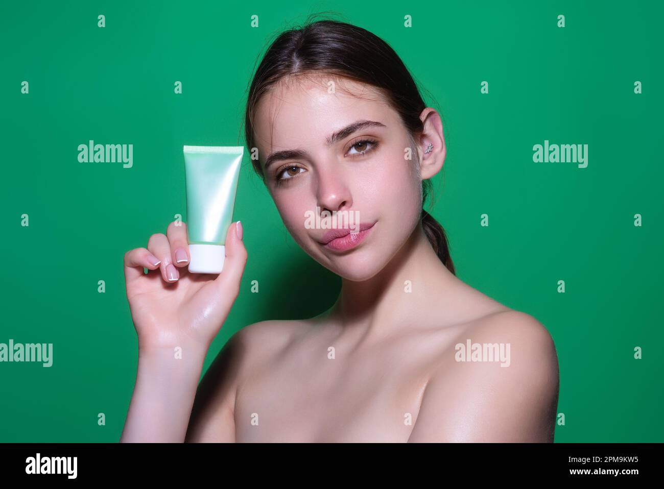 Skin care. Woman applying face cream, studio portrait. Beautiful model ...