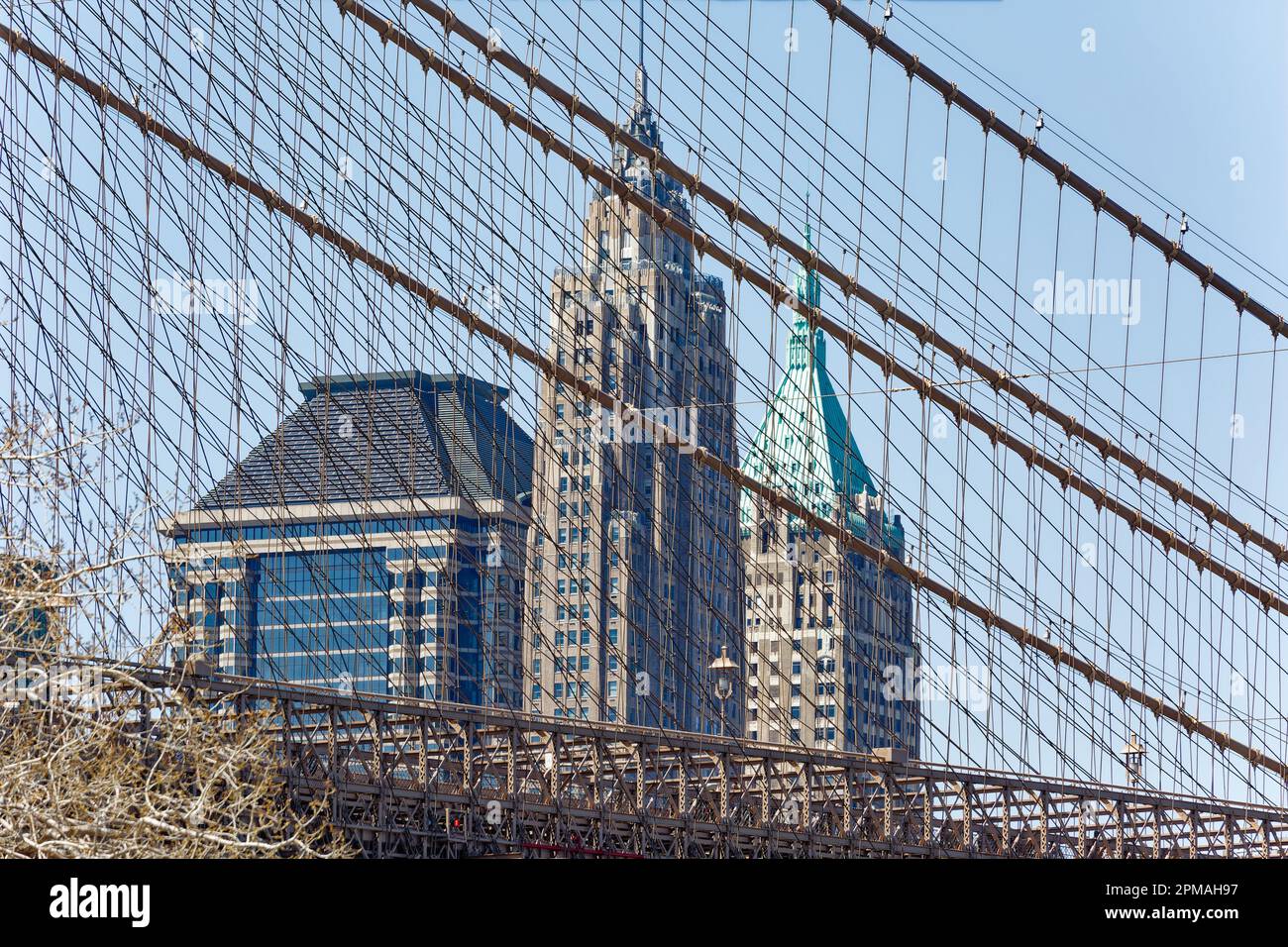 Cables and stays of the Brooklyn Bridge veil Financial District skyscrapers 60 Wall Street, 70 Pine Street, and 40 Wall Street. Stock Photo