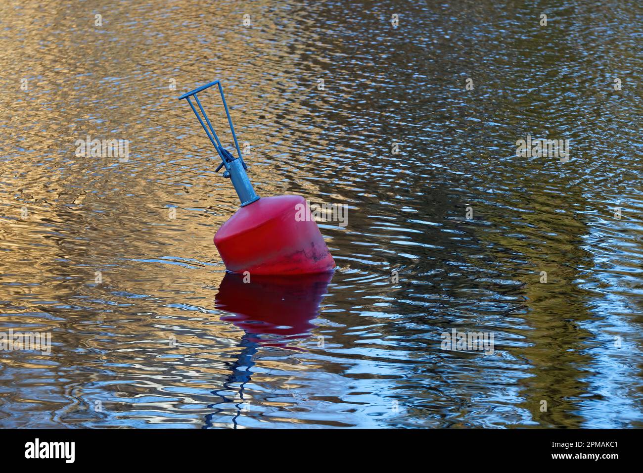 A red buoy floats on the surface of the lake Stock Photo