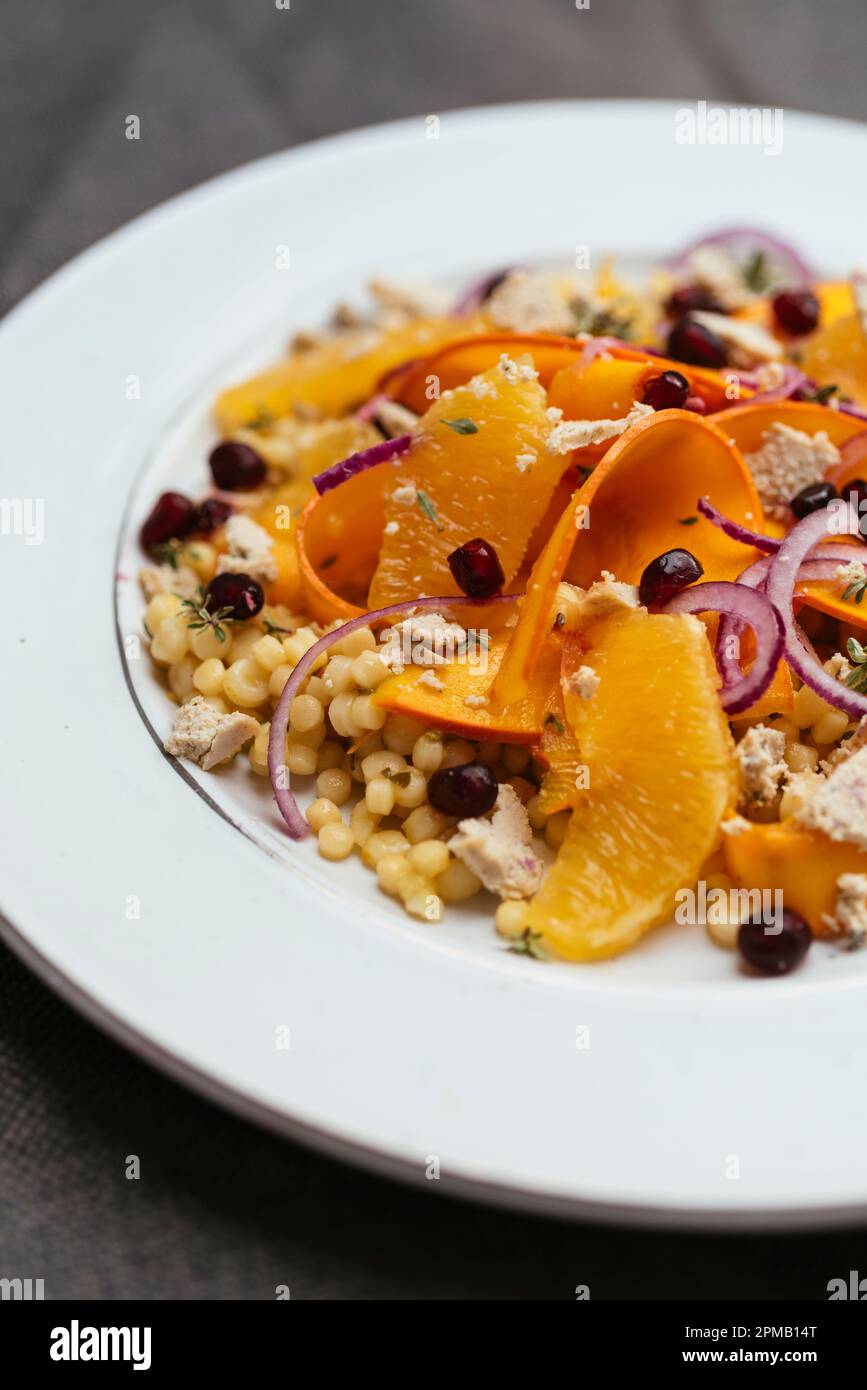 Salad with marinated winter squash, oranges and vegan feta on pearl couscous. Stock Photo