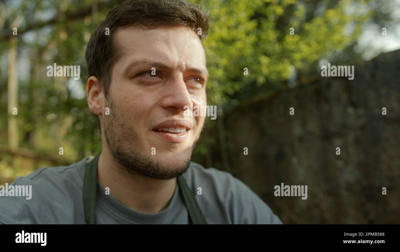 Young handsome farmer resting and catching his breath while sitting on
