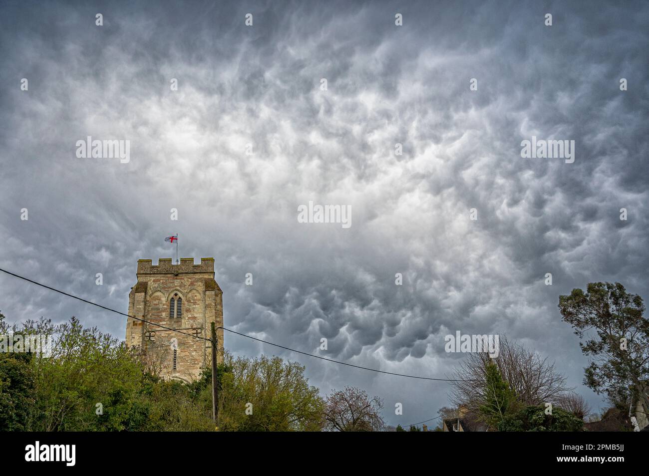 Orwell,  Cambridgeshire, UK. 12th Apr, 2023. Mammatus clouds fill the sky over St Andrew's Church The weather in the east of England today consisted of April showers, gusty winds and lower than average temperatures. Mammatus clouds are unusual in that they often form on the underside of storm clouds and are a result of sinking, rather than rising air. Credit: Julian Eales/Alamy Live News Stock Photo