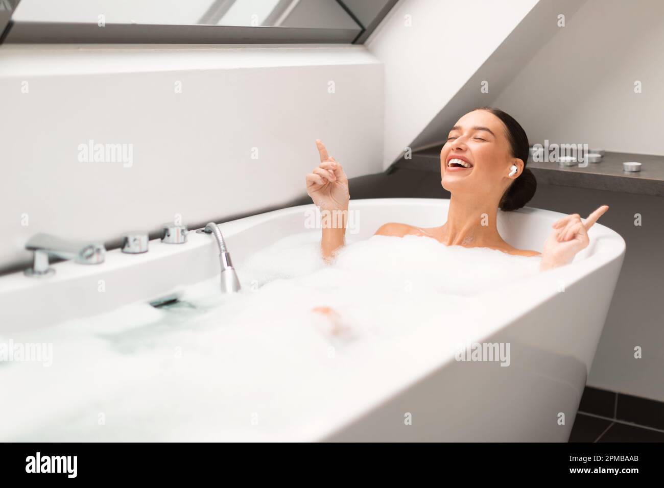 Woman Taking Bath Enjoying Relaxing Playlist Wearing Earbuds In